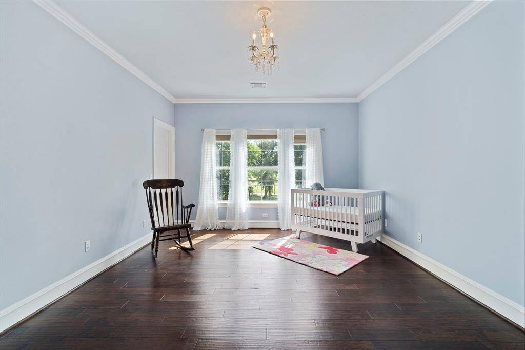 Secondary bedroom features largewindows, chandelier, custom paint, and beautiful flooring.