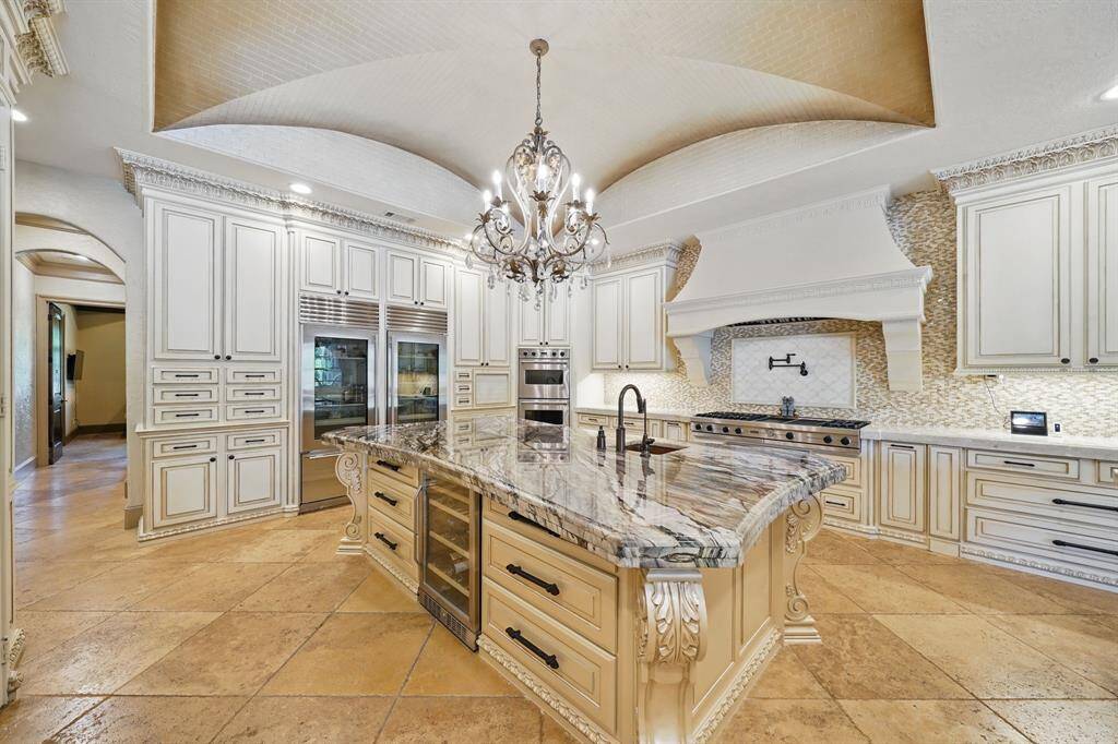 Right above the island is another beautiful chandelier. The kitchen features light cabinets, tile floors, beautiful counters, and luxury stainless steel appliances, this kitchen creates a clean and timelessaesthetic.