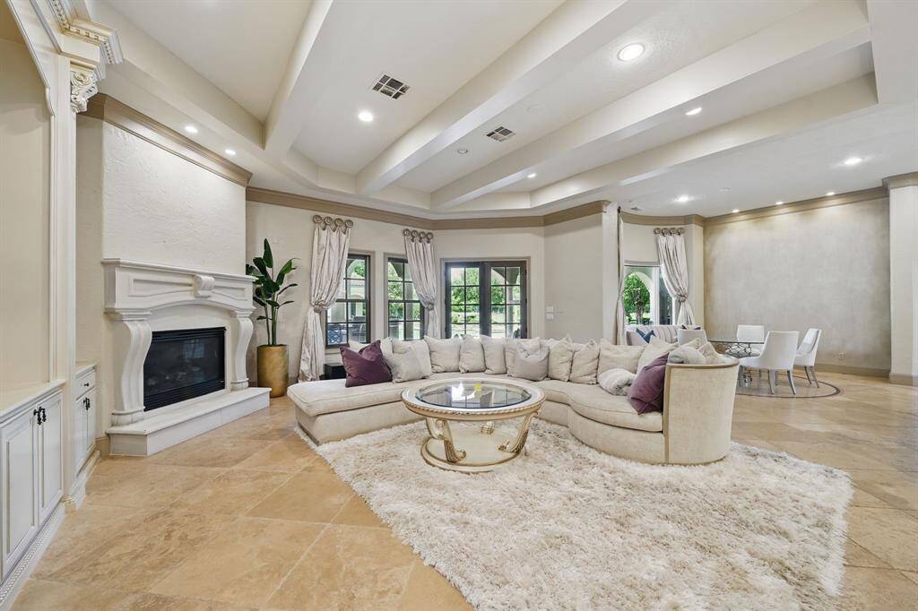 The sitting room features tile floors, recessed lighting, beamed ceilings, large windows, and a cozy fireplace.