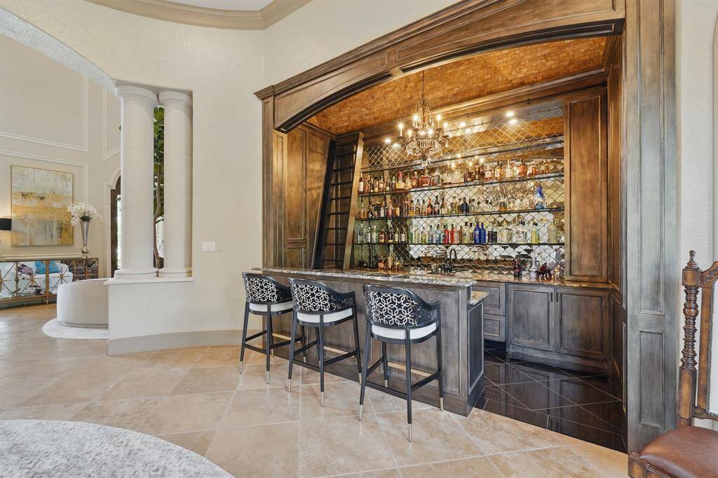 The wet bar features spacious countertops, tile floors, chandelier, and sliding ladder.