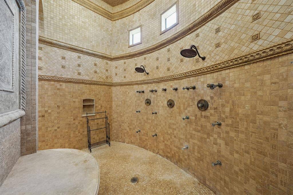 The huge walk-in shower has multiple shower heads and sprayers.