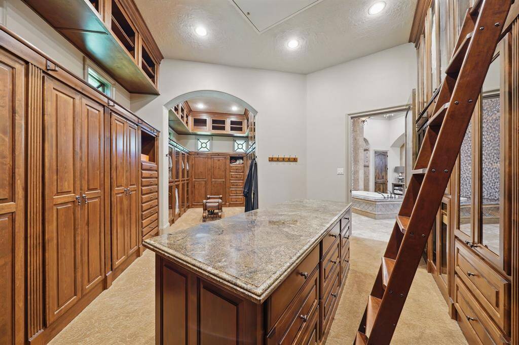 The primary closet has plush carpet, island, sliding ladder, and plenty of storage space.