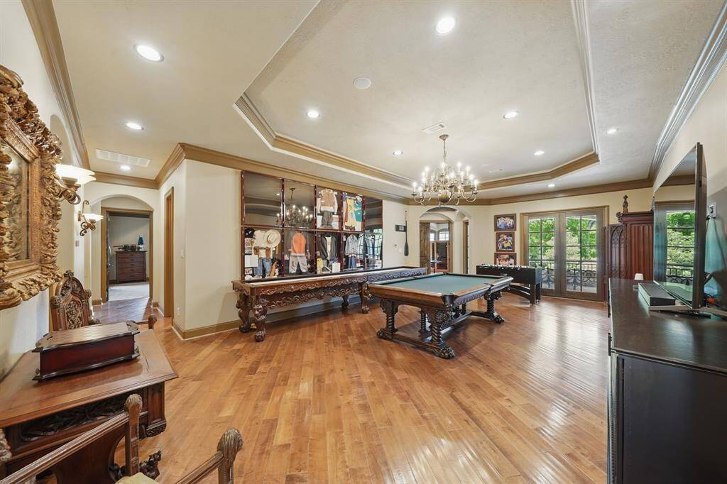 The billiard room features beautiful floors, high ceilings, recessed lighting, chandelier, and access to the covered balcony.