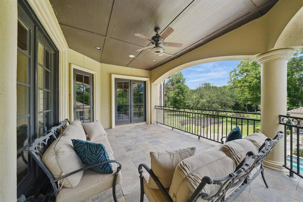 The covered balcony overlooks the backyard and features tile flooring, recessed lighting, and an outdoor ceiling fan.