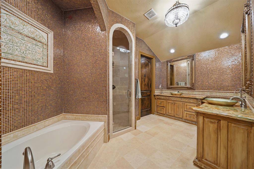 Secondary bathroom features tile floors, dual vessel sinks, walk-in shower, and separate soaking tub.