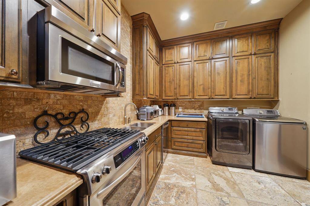 The additional kitchen and laundry area features tile floors, spacious countertops, wood cabinets, and stainless steel appliances.