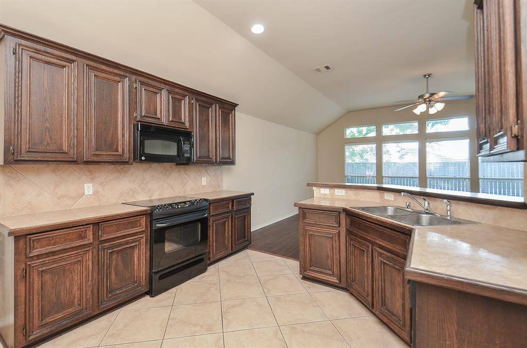 The kitchen offers ample wood cabinets and open hanging shelves, providing generous storage with a warm, classic look.