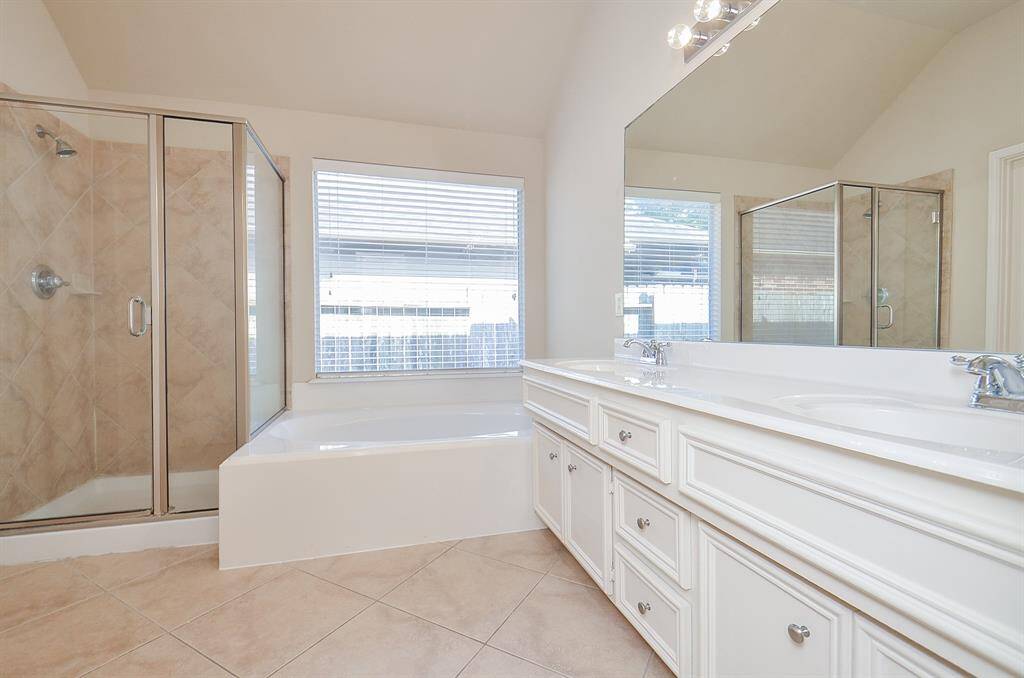 Primary bathroom featuring a deep soaking tub and a sleek glass-enclosed shower for a spa-like retreat.