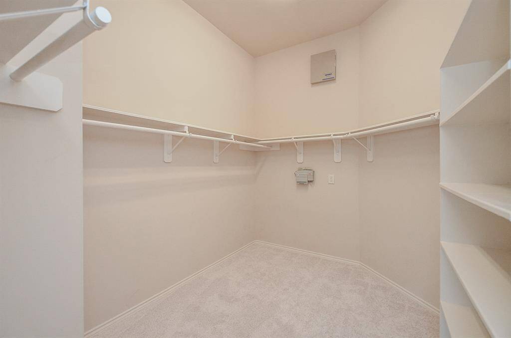 Spacious walk-in closet featuring multiple hanging rods and a built-in open shelving, providing ample space for organizing clothing.
