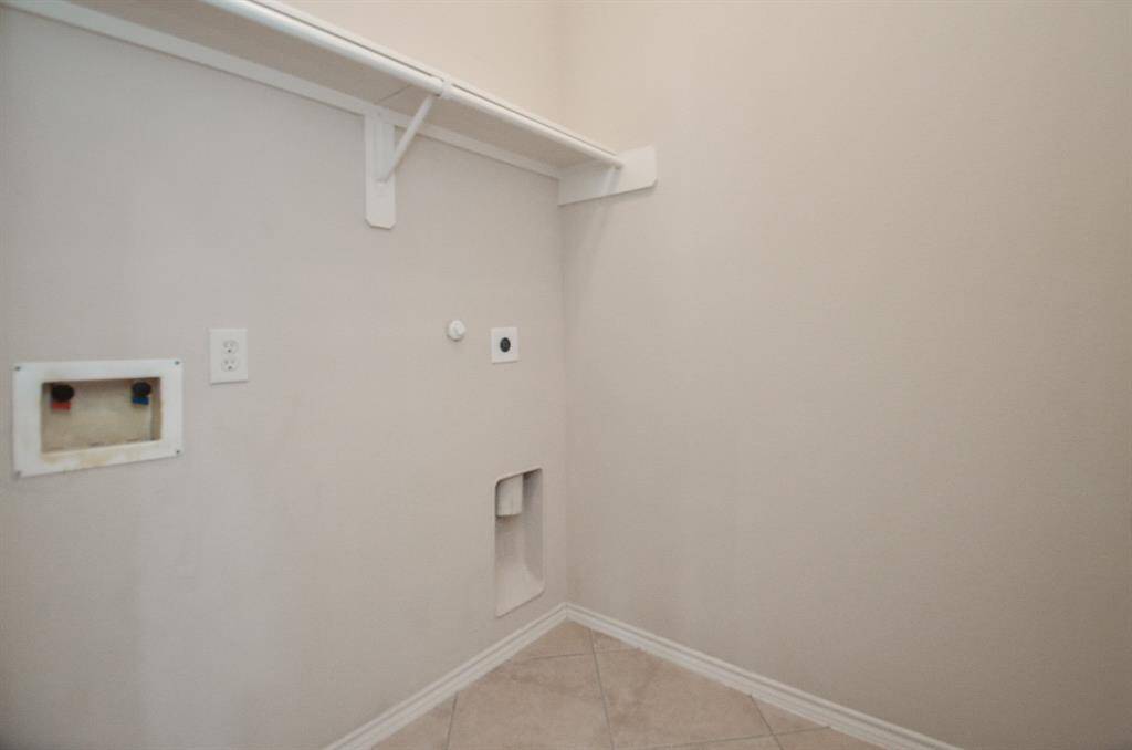 Convenient laundry area with overhead shelving offering easy access to laundry essentials.