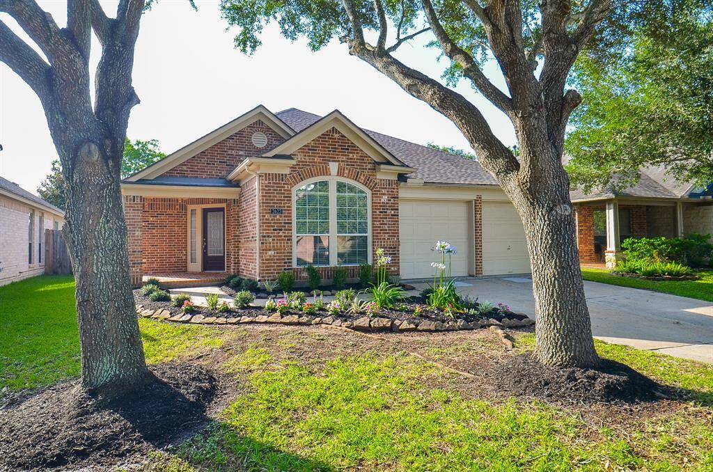 This home features a spacious driveway with two-car attached garage complemented by mature shade trees and a beautifully landscaped front yard