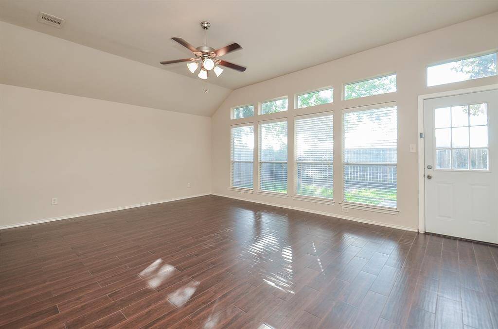 The living room features elegant wood-look flooring and soaring high ceilings, creating a warm and airy ambiance.