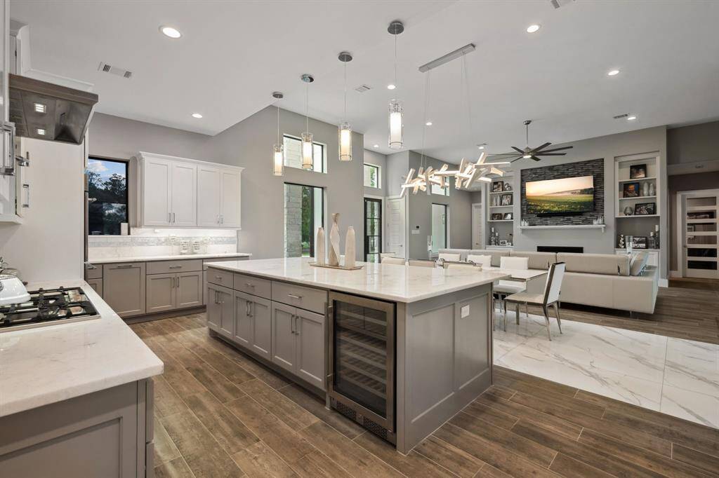 The kitchen features a sleek gas stovetop, a dedicated wine refrigerator, and a convenient double sink, combining style and functionality for a superior cooking experience.