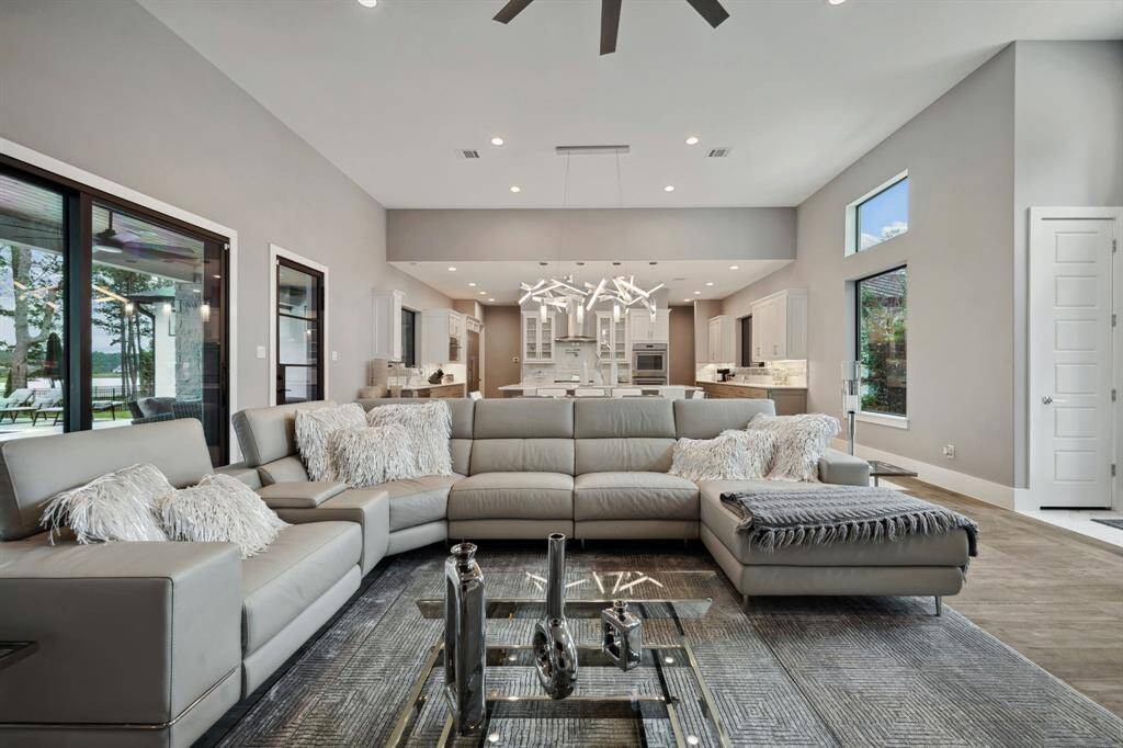 This inviting living room seamlessly flows into an expansive outdoor retreat, featuring a covered patio, a fully equipped outdoor kitchen, and a sparkling pool.