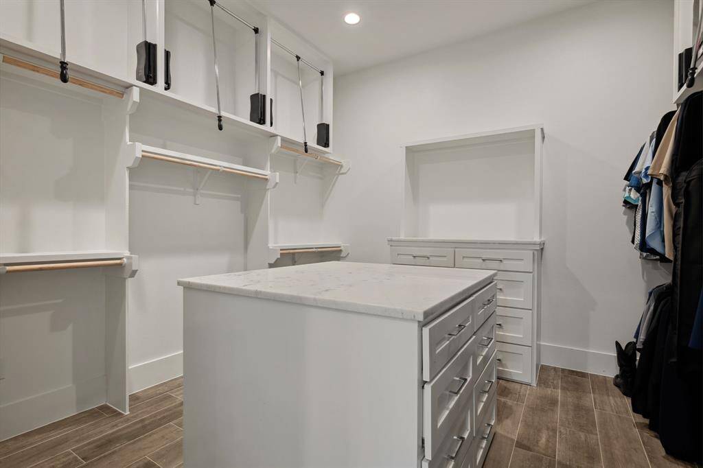 A generously sized walk-in closet featuring a central island and abundant storage space for effortless organization.
