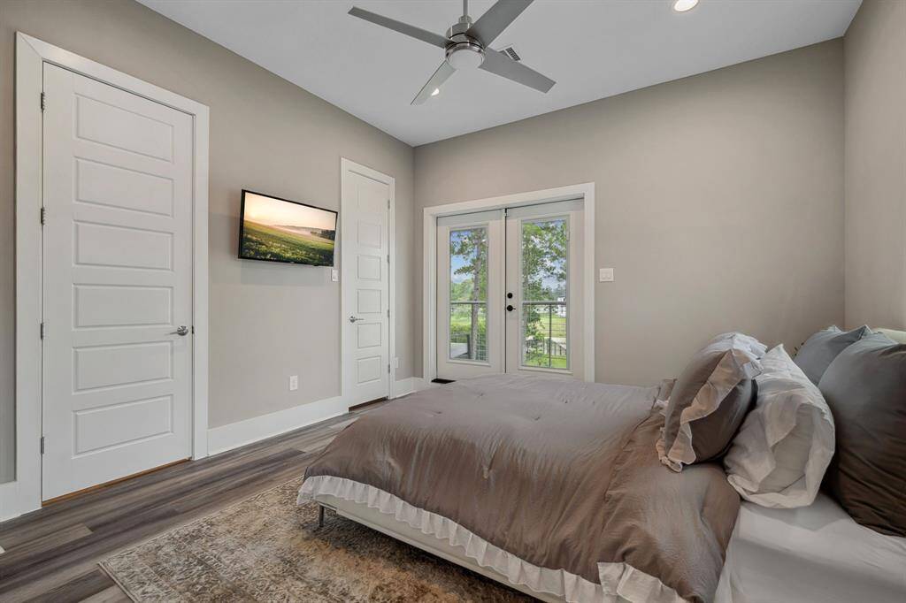 A generously sized bedroom featuring a private ensuite bathroom and a balcony overlooking the serene backyard and picturesque lake views. Two bedrooms are located on the second floor.