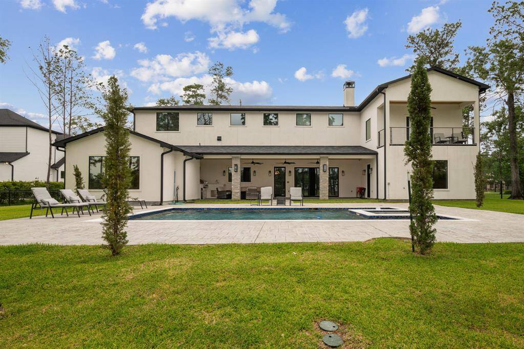 Backyard featuring a stunning lake view, a luxurious pool and jacuzzi, a fully equipped outdoor kitchen, and a spacious covered patio—perfect for relaxation and entertainment.