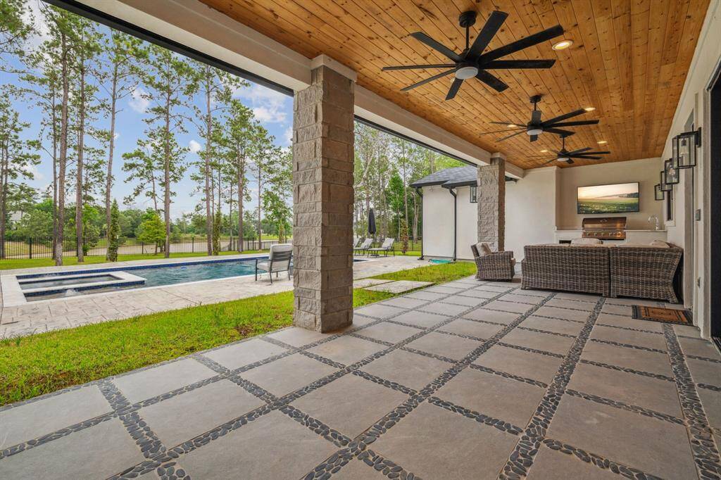 A beautifully crafted wooden-covered ceiling, complete with fans and ambient lighting, shelters a fully equipped outdoor kitchen—perfect for hosting unforgettable gatherings with family and friends.