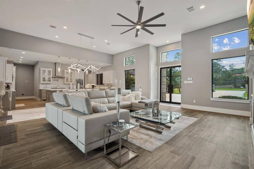 Featuring soaring ceilings and elegant neutral-toned flooring, this living room is adorned with striking lighting fixtures, exquisite built-ins, and expansive walls of windows that invite an abundance of natural light.