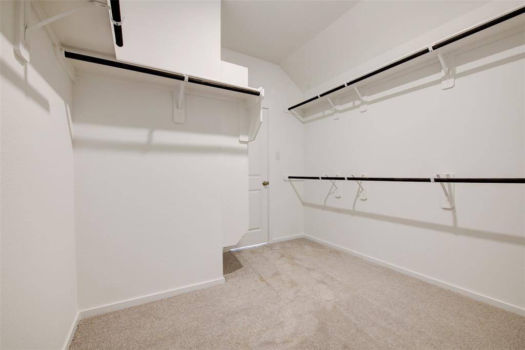 Well-lit walk-in closet with carpeted flooring