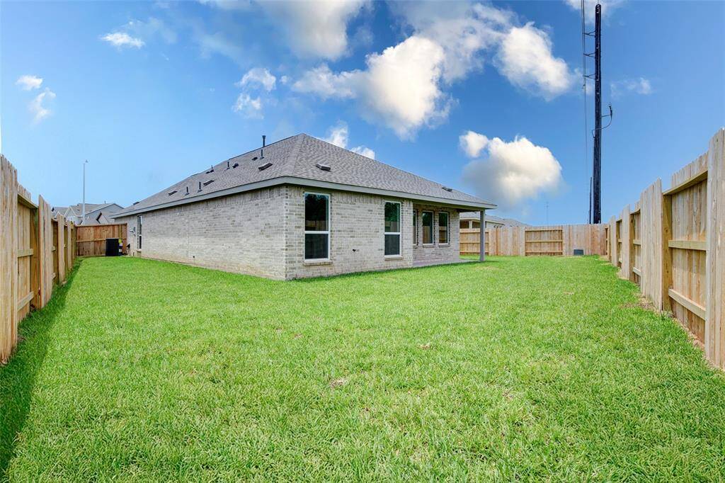 Spacious fenced-in backyard with lush green grass