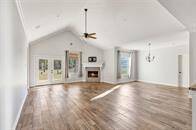 This is a spacious, open-concept living area with a cozy fireplace, elegant tray ceilings, and a seamless flow into the dining and kitchen spaces, featuring modern finishes and ample natural light.