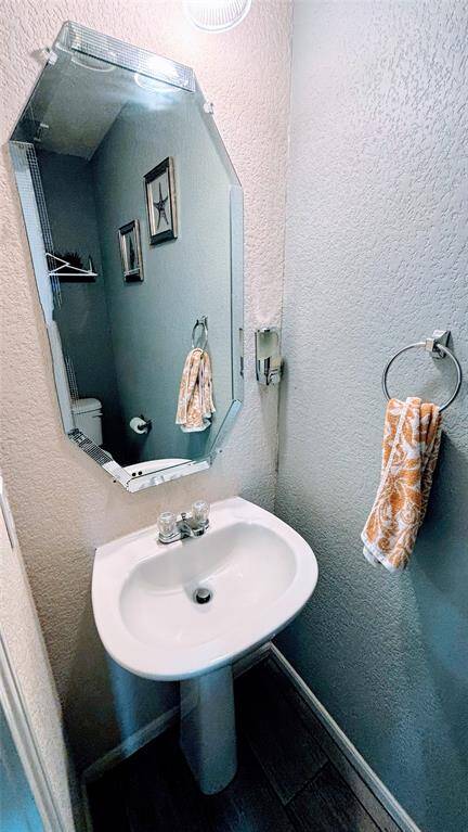 A compact bathroom with a pedestal sink and a large, angular mirror.