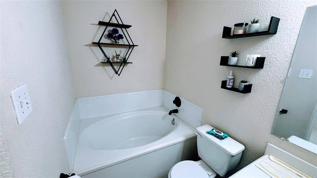 This Master bathroom features a cozy corner bathtub with a sleek black faucet.
