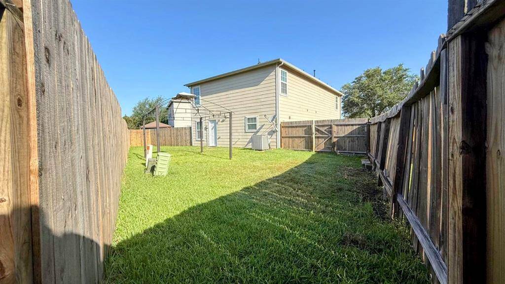 Spacious backyard with well-maintained lawn, surrounded by wooden fencing for privacy. Ideal for outdoor activities and relaxation.