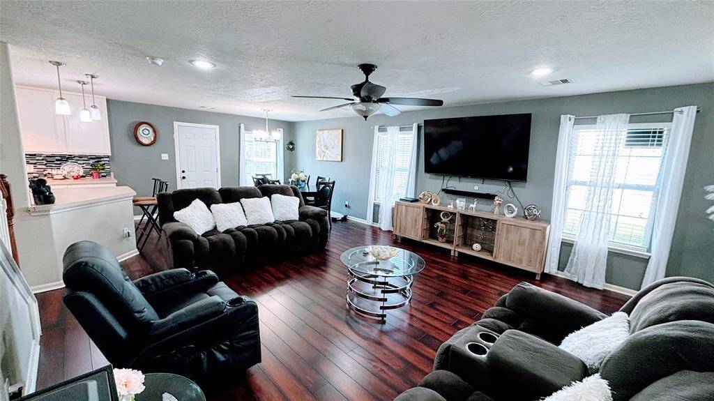 This spacious bright living area features rich hardwood floors and a ceiling fan.