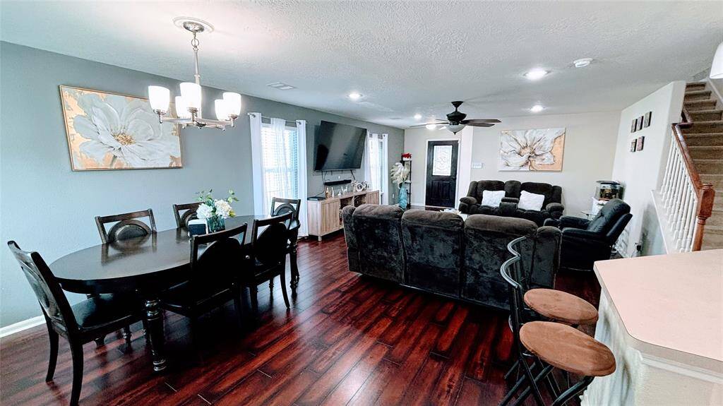 This inviting open-concept living and dining area features rich hardwood floors and modern decor. The space is well-lit with large windows.