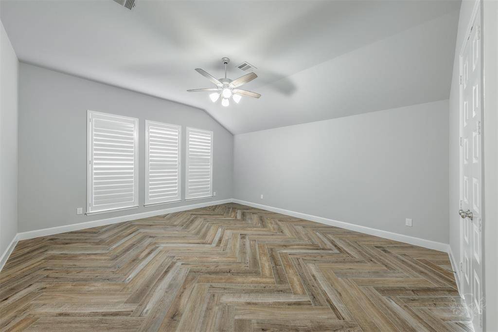 Primary bedroom. Notice the plantation shutters and beautifully laid herringbone pattern with the wood-look floor tiles.