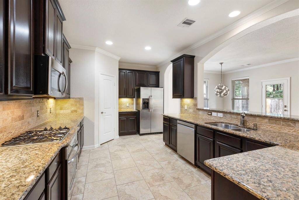 This kitchen is equipped with high-quality stainless-steel appliances, including an LG dishwasher and GE appliances—highlighted by a sleek side-by-side refrigerator (included with home) and a built-in gas cooktop perfect for the home chef.