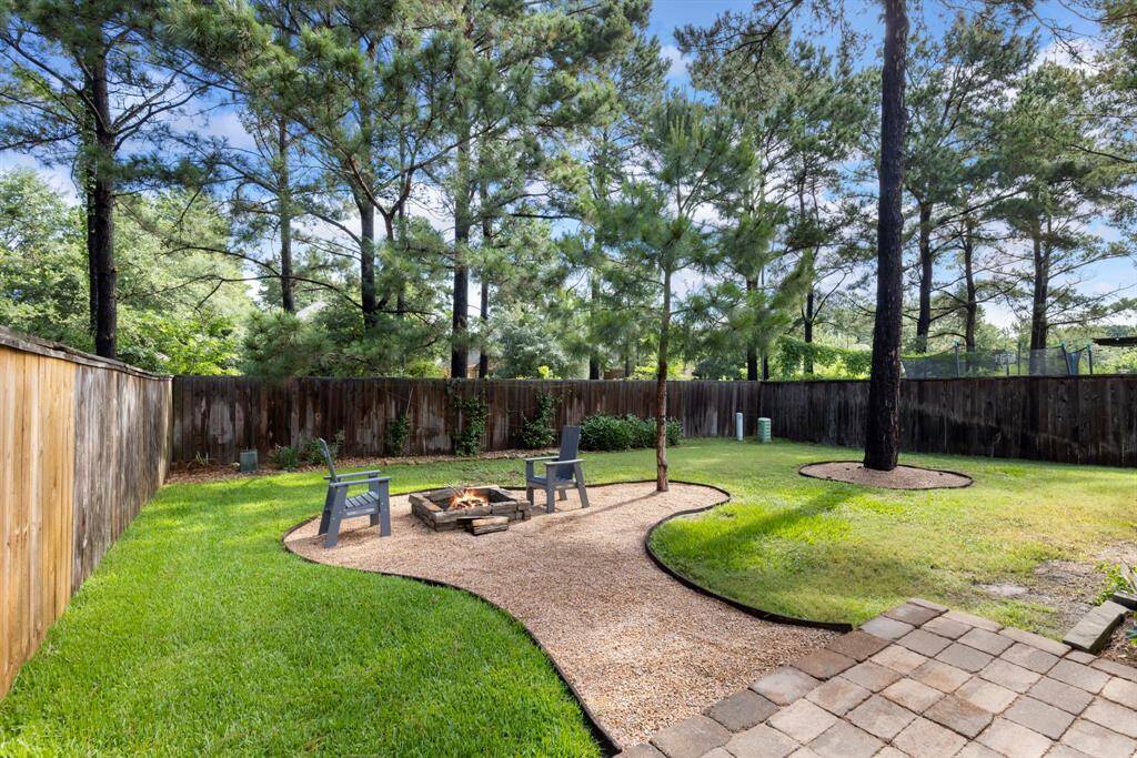 From the patio, an extended walkway finished in elegant granite guides you through the lush green lawn to a charming granite sitting area, centered around a built-in firepit. Whether you're roasting marshmallows or enjoying quiet evenings under the stars, this cozy nook is ideal for gathering with friends and family.