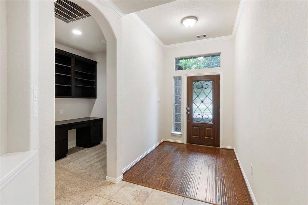 The entry features a solid wood front door with beveled glass and wrought iron accent, wood floor entry and crown moulding.