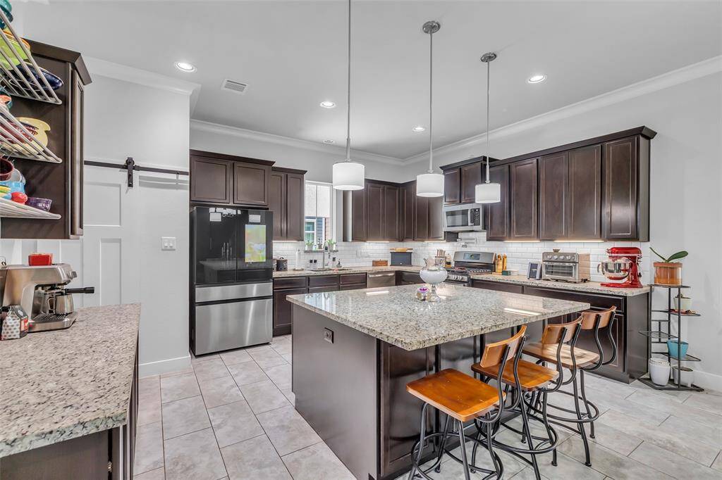 The kitchen island without a cooktop doubles as a prep station and breakfast bar, with storage on both sides and stylish drop lighting overhead that adds both function and character to the space.