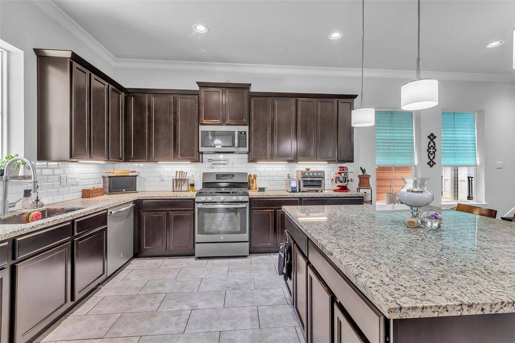 The kitchen features ample chocolate-stained cabinets and drawers, providing generous storage throughout the space, and includes a convenient pot filler above the range for added functionality.
