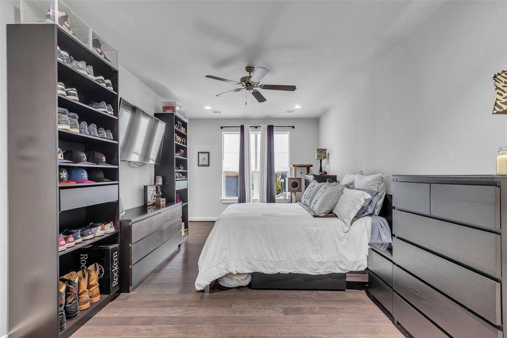 This third-floor primary bedroom features a spacious layout with a large window on the opposite wall, allowing natural light to fill the room.