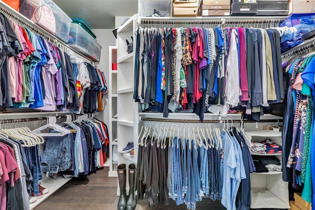The larger walk-in closet in the third-floor primary bedroom includes multiple racks, built-in shelves, and a dedicated built-in shoe shelf, providing ample space to organize your belongings efficiently.