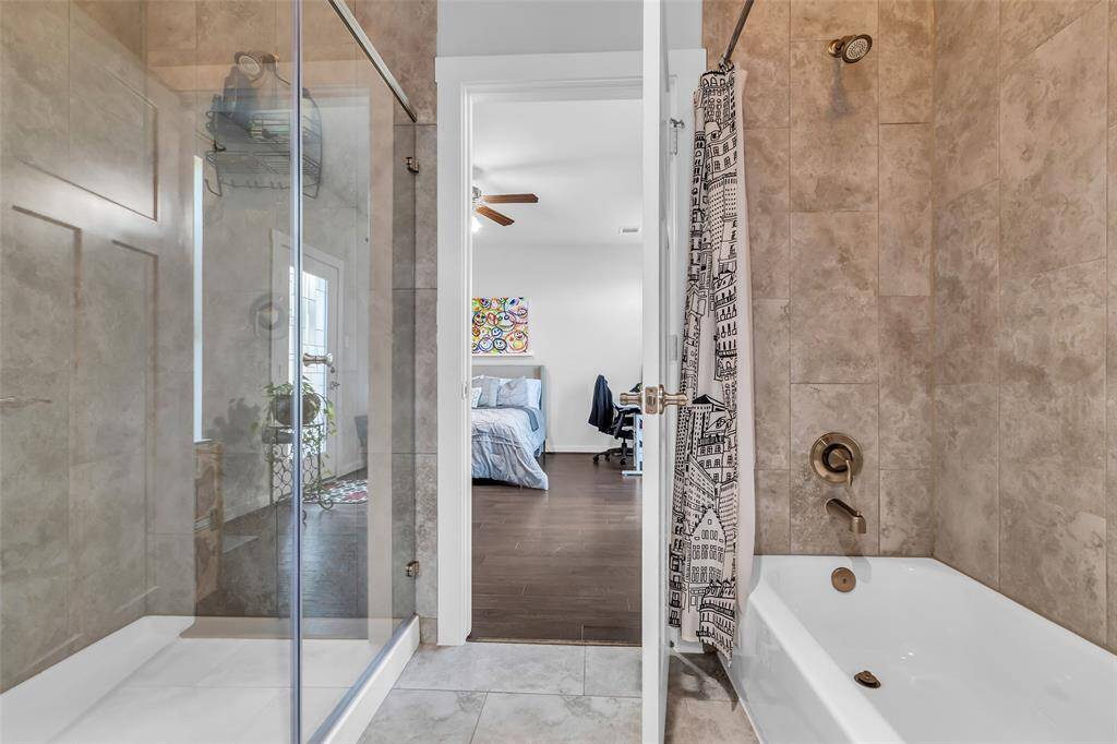 Located on the first floor, this primary bathroom features both a separate shower and a tub-shower combination. Travertine tile on the walls adds a refined touch and lasting durability.
