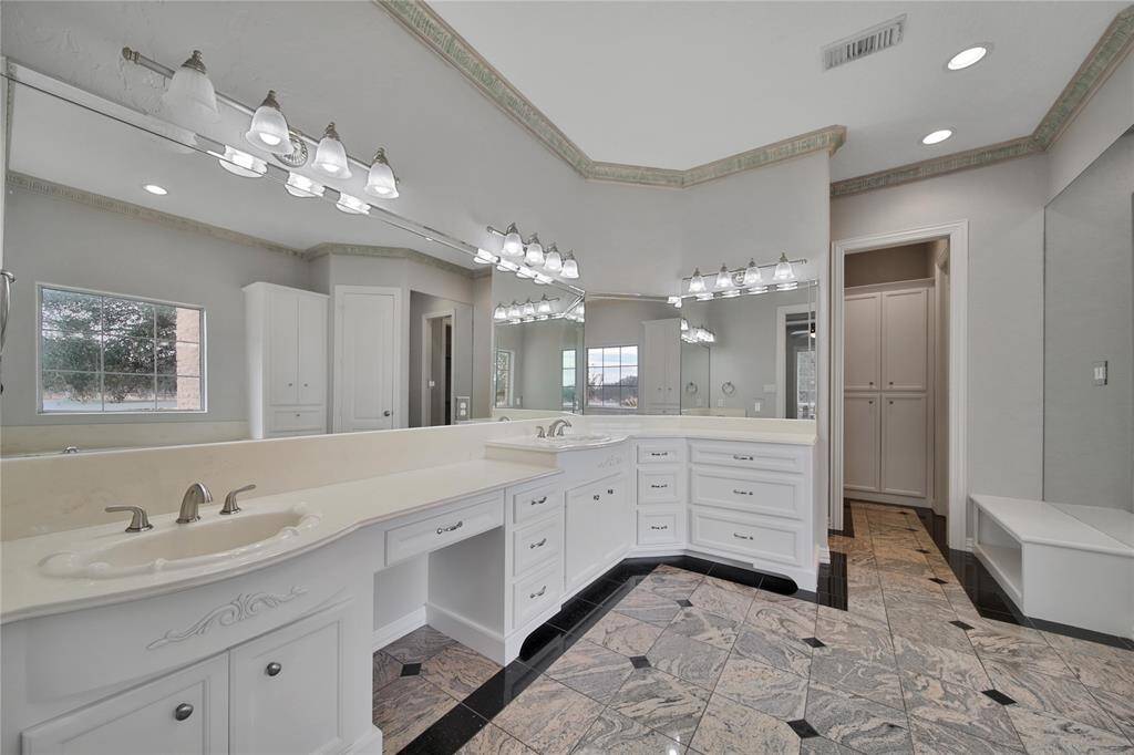 Luxurious primary bath featuring double vanities, whirlpool tub, separate shower, and dual walk-in closets.
