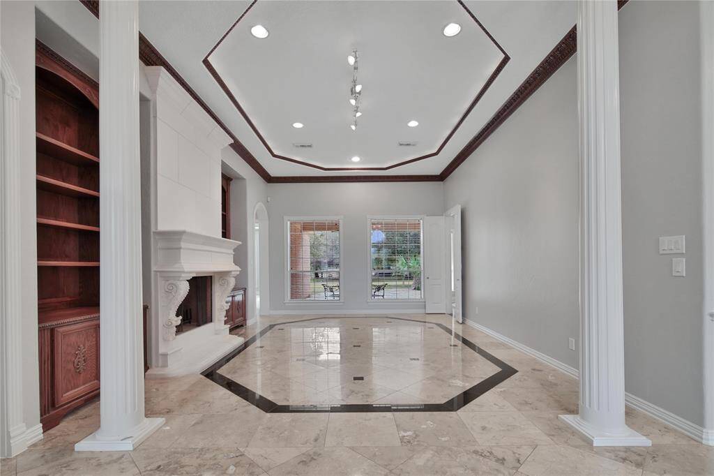 Formal living room with columns, built-ins flanking a wood-burning fireplace.