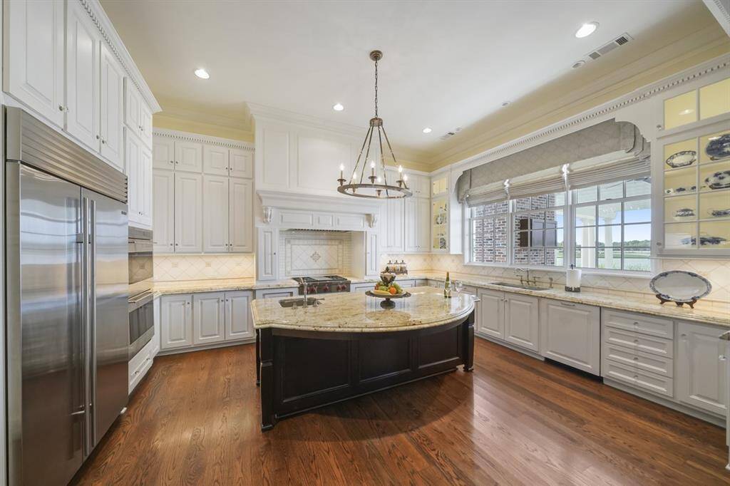 Spacious kitchen with 6cm Level 3 Colonial Cream Granite countertops from Austin. Chef's dream with Stainless Steel appliances: WOLF gas range and griddle, built-in SUB-ZERO refrigerator, WOLF double convection ovens, integrated dishwasher, and built-in microwave. Extensive paneled cabinetry has incredible storage with pull-out drawers and Lazy Susan drawers. Lighted cabinets and under cabinet lighting. Extensive trimwork with dentil trim detailing