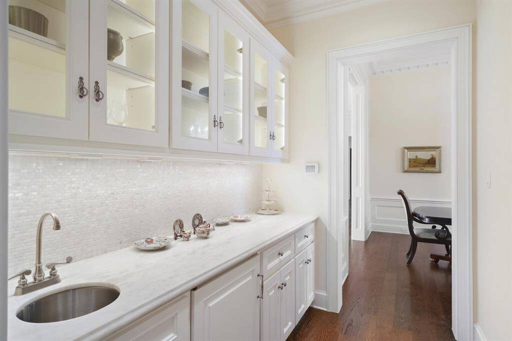 Wet bar/butler's pantry connects to formal dining room for convenient prep and has authentic Mother-of-Pearl backsplash and Sugar White counter. Undercounter SUB-ZERO refrigerator/ice maker and inside cabinet lighting and under cabinet lighting.