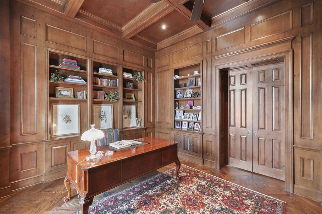 Smooth Alder pocket doors provide privacy and opens to a handsome paneled and stained primary study with texturing applied by the fingertips. Coffered ceiling complemented with a ceiling fan. Abundance of cabinetry and shelving ideal for displaying artwork and books.
