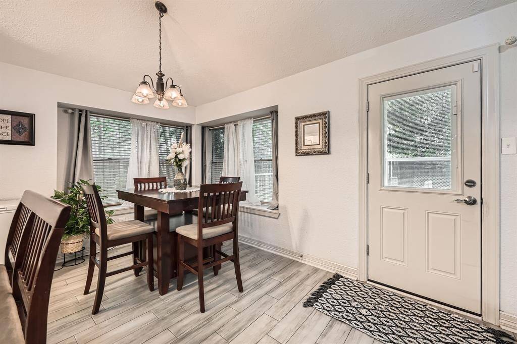 3106 Village Springs Ct. This cozy dining area features large windows with ample natural light, a stylish light fixture, and a door leading outside. The space is accented with a modern tile floor and neutral walls, providing a welcoming atmosphere.