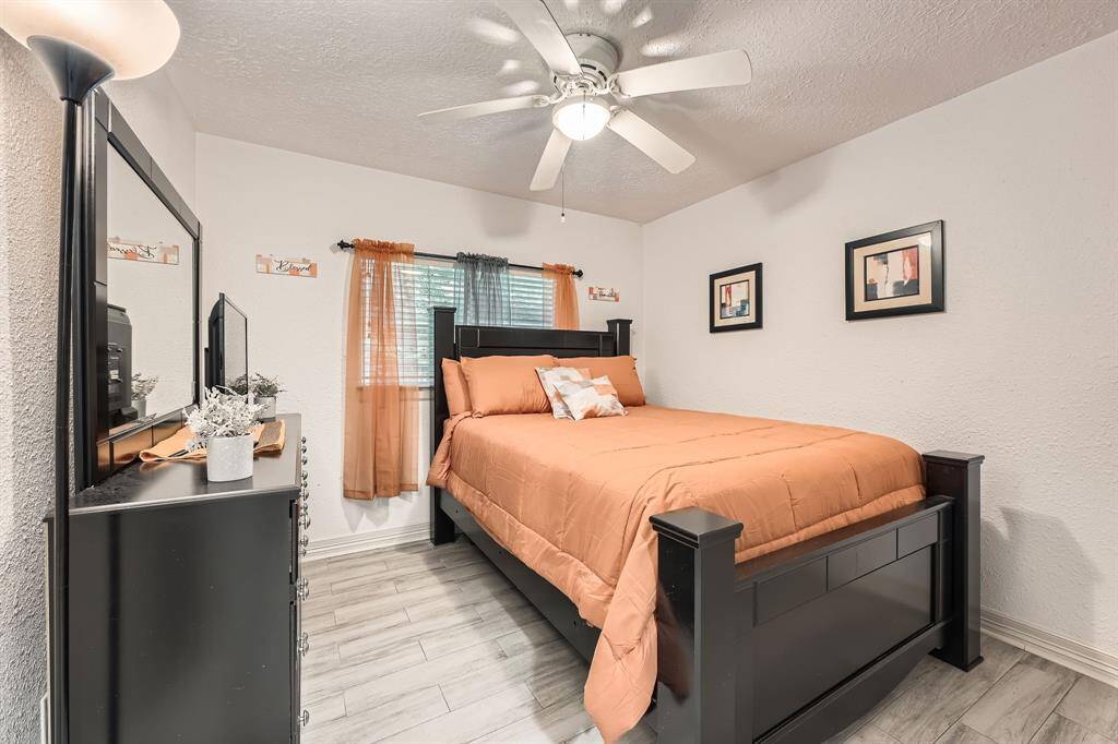 3106 Village Springs Ct. This third cozy bedroom features a modern design with a ceiling fan, neutral walls, and wood-look flooring. Natural light streams in through a window ,creating a welcoming atmosphere.