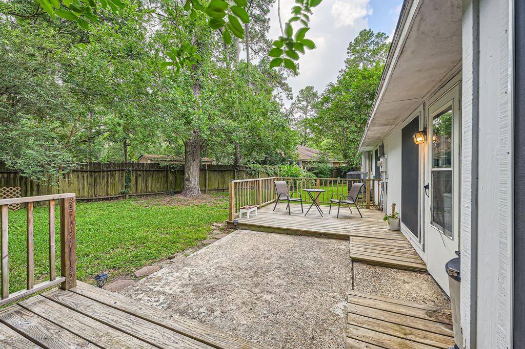 3106 Village Springs CT. Charming backyard with a cozy wooden deck, perfect for outdoor dining and relaxation. Surrounded by lush greenery and a sturdy fence for privacy, this space offers a tranquil retreat.