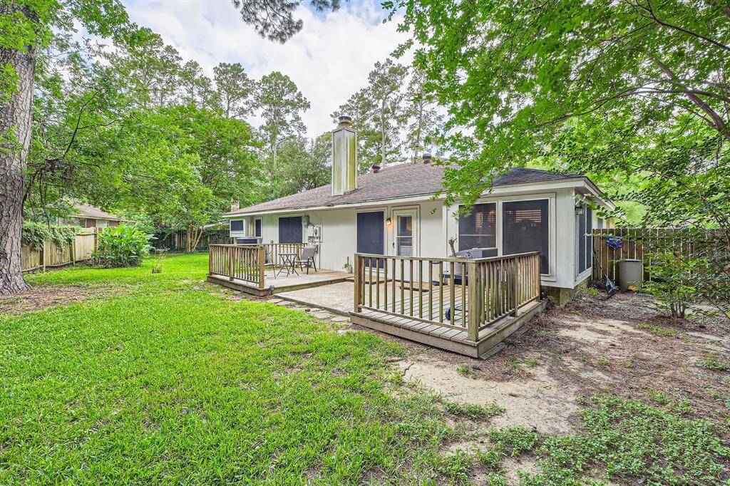 3106 Village Springs Ct this Cozy home with a spacious backyard featuring a wooden deck, surrounded by lush greenery and mature trees, providing a serene outdoor space for relaxation or entertaining.