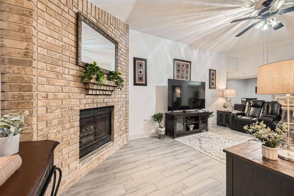3106 Village Springs Ct This cozy living room features a brick fireplace, modern tile flooring, and a ceiling fan.